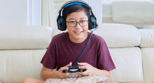 Boy playing minecraft with headphones on a console